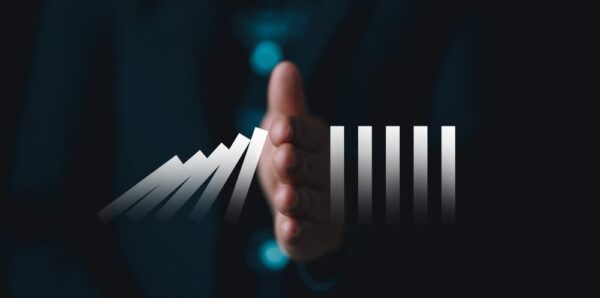 A hand stopping dominos from falling.